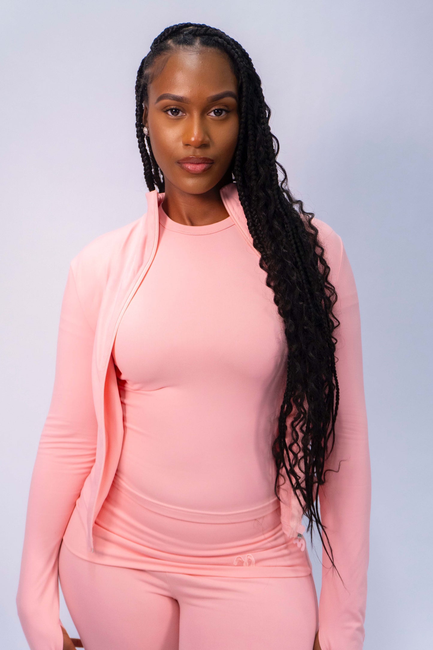 Woman in a pink tracksuit with long braided hair.